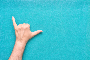 gesture with man's left hand of relaxation shaka or drink in man hand on glow turquoise background