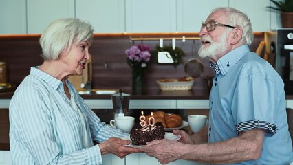 Senior couple celebrating birthday at home. Elderly man and woman with 80 year birthday cake