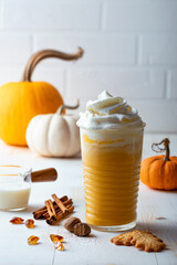 Spicy pumpkin latte with whipped cream. Autumn or winter hot coffee drink with cinnamon, nutmeg and cookies