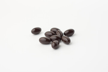 Black soft gel capsules on a white background. Vitamin food supplements
