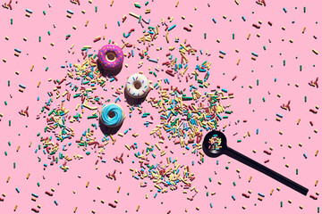 Trendy sunlight seamless pattern made of three colorful doughnut toys and sprinkle candy with sharp shadow on pink background. Minimal food summer concept with copy space.