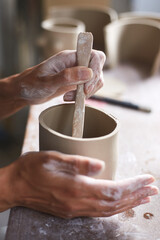 Obraz na płótnie Canvas Female ceramist working in pottery studio. Ceramist's Hands Dirty Of Clay. Process of creating pottery. Master ceramist works in her studio
