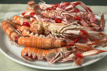 Norway lobster roe. Bowl with several crayfish. White bowl on a black table.