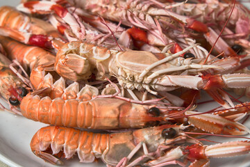 Norway lobster roe. Bowl with several crayfish. White bowl on a black table.