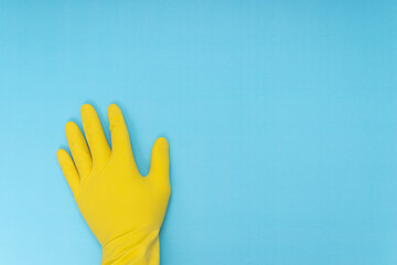 Fototapeta premium yellow cleaning glove standing on blue background.home cleaning