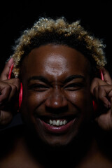 An African American man is delighted with the music he listens to in red wireless on a black background