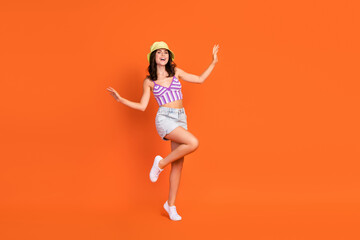 Fototapeta na wymiar Full length photo of brunette crazy lady dance wear hat top jeans shorts shoes isolated on orange color background
