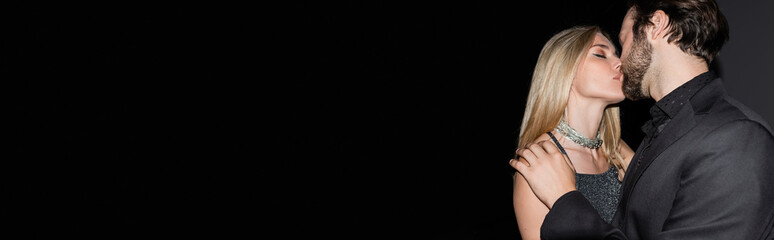 Sexy blonde woman kissing boyfriend in jacket on black background, banner.