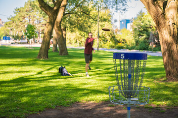 Disc golf, a flying disc sport played using rules like golf, being played by a middle aged man on a...