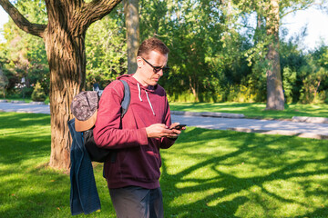 Disc golf, a flying disc sport played using rules like golf, here  a middle aged man uses a phone...