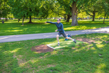 Disc golf, a flying disc sport played using rules like golf, being played by a middle aged man on a...