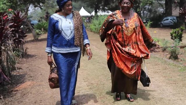 Two African women walk while having a conversation, they are traditionally dressed
