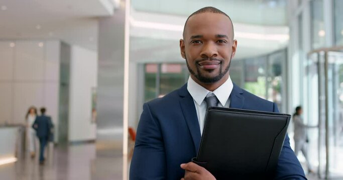 Portrait of corporate business manager, office lobby and busy conference foyer with executive suit, entrepreneur folder and professional company. Success, smile and leadership black man ready for job