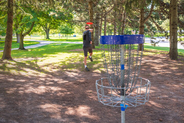 Disc golf, a flying disc sport played using rules like golf, being played by a middle aged man on a...