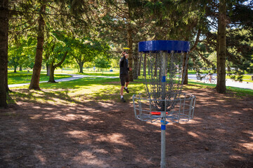 Disc golf, a flying disc sport played using rules like golf, being played by a middle aged man on a nine hole course in  Ashbridges Bay Park in Toronto’s Beaches neighbourhood in late August.
