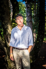 Beautiful blue-eyed man is wearing a white shirt and bedge pants. Businessman is working outdoors in the park.