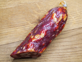 Half of an appetizing sausage on a wooden background, close-up shot. Food on a cutting board. Smoked sausage on a rustic table.