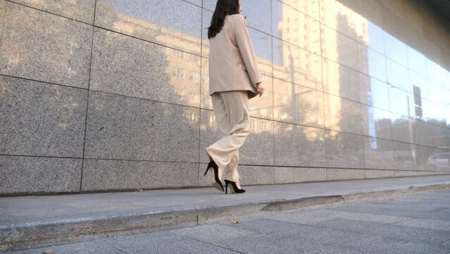 Unrecognizable business woman walking near modern building. Confident businesswoman in suit going on city street to meeting in office. Successful lady in formal wear commuting to work. Slow motion