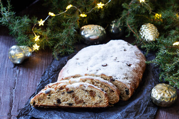 Christmas stollen with dried fruits, nuts and spices, Christmas decorations on a dark wooden background. Rustic style.