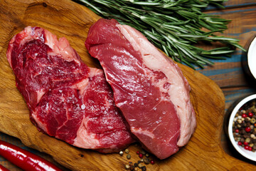 Raw organic beef meat with rosemary, seasonings, salt and red pepper  on wooden cutting board