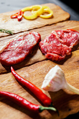Raw organic beef meat with rosemary, seasonings, salt and red pepper  on wooden cutting board