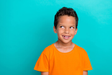 Photo of pretty dreamy small man wear yellow t-shirt smiling looking empty space isolated turquoise...