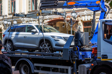 Fototapeta na wymiar Loading a car onto a tow truck in a narrow street of the old city.