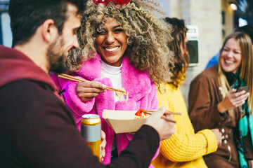 Happy multiracial friends eating takeaway food outdoor - Focus on african girl face