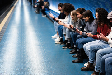 Young multiracial friends having fun using mobile phones inside subway station - Focus on right...
