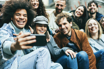 Young diverse people using mobile phone doing selfie outdoor - Focus on african guy face