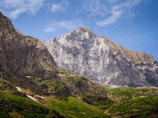 Montaña rocosa de los Pirineos bajo un cielo azul con angunas nubes blancas.