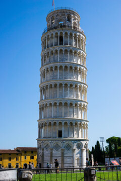 Pisa, Toscana , Italia 08-28-2022.  A picturesque portrait shot of the famous Pisa Leaning Tower on a beautiful day at dusk with a blue sky, and the sun shines on the white marbled campanile.