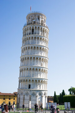 Pisa, Toscana , Italia 08-28-2022.  A picturesque portrait shot of the famous Pisa Leaning Tower on a beautiful day at dusk with a blue sky, and the sun shines on the white marbled campanile.