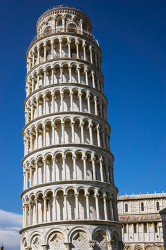 Pisa, Toscana , Italia 08-28-2022.  A picturesque portrait shot of the famous Pisa Leaning Tower on a beautiful day at dusk with a blue sky, and the sun shines on the white marbled campanile.