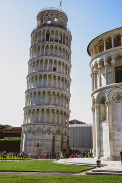 Pisa, Toscana , Italia 08-28-2022.  A picturesque portrait shot of the famous Pisa Leaning Tower on a beautiful day at dusk with a blue sky, and the sun shines on the white marbled campanile.