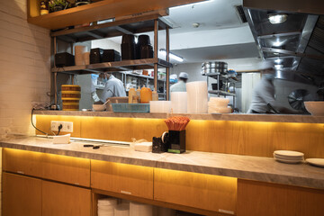 Kitchen of an Asian cuisine restaurant with staff busy cooking and working on the background
