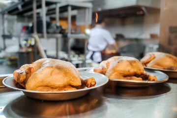 Chicken meat menu prepared in a restaurant kitchen with chef and staff working on the background