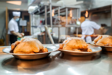 Chicken meat menu prepared in a restaurant kitchen with chef and staff working on the background