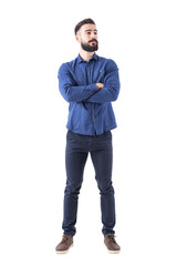 Confident cool young bearded man standing and looking away with crossed hands. Full body isolated...