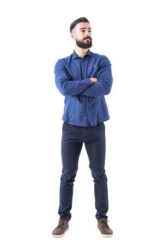 Confident cool young bearded man standing and looking away with crossed hands. Full body isolated on transparent background.