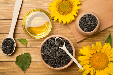 Sunflower oil, seeds and flower on wooden background, top view