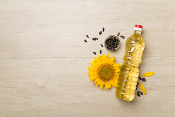 Sunflower oil, seeds and flower on wooden background, top view