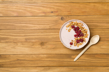 Bowl with granola, yogurt and fresh berries on wooden background, top view