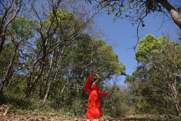 a beatiful Indian girl in red dress wondering in nature