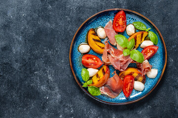 Grilled peach salad with mozzarella, prosciutto ham, red tomato, green basil and soy sauce