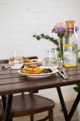 The table with breakfast of sandwiches and fried eggs, glasses of water with lemon.