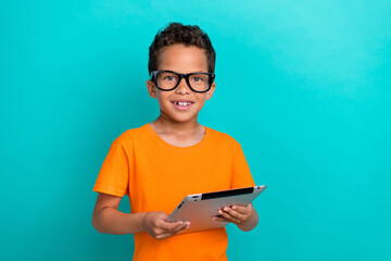 Photo of pretty cute small man wear yellow t-shirt eyeglasses chatting facebook telegram modern device isolated turquoise color background - obrazy, fototapety, plakaty