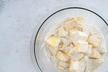 cubes cold butter  in a glass bowl with all-purpose flour in preparation to make puff pastry , basic puff pastry ingredients.