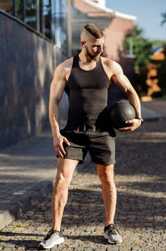Muscular man or fitness coach with fitness weight ball outdoors