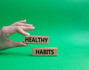 Healthy habits symbol. Concept word Healthy habits on wooden blocks. Beautiful green background. Businessman hand. Business and Healthy habits concept. Copy space